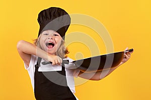Little cook with cooking pan. Portrait of little child in uniform of cook. Chef boy isolated on studio background. Cute