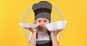 Little cook with cooking plate. Portrait of little child in uniform of cook. Chef boy isolated on studio background