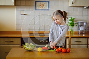 Little cook cooks salad. On a table various vegetables.