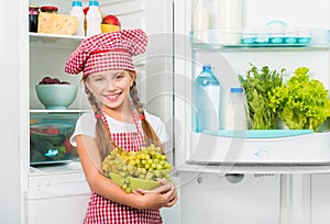 Little cook girl holding grapes