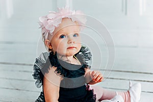 Little crawling baby girl one year old siting on floor in bright light living room smiling and laughing