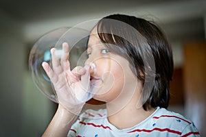 Little creative kid having fun with soap bubble during lockdown