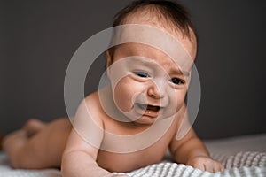 Little crying baby daughter on bed. One month age. Newborn cute happy beautiful girl smiling. Breast-feeding. Happiness
