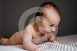 Little crying baby daughter on bed. One month age. Newborn cute happy beautiful girl smiling. Breast-feeding. Happiness