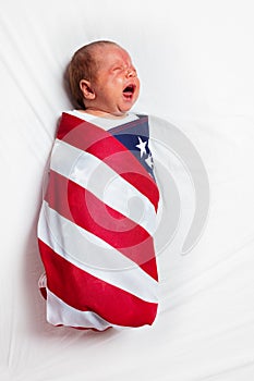 Little crying baby infant wrapped in USA flag