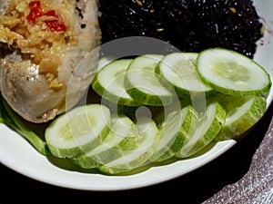 A little cucumber on a plate of chicken rice with brown rice