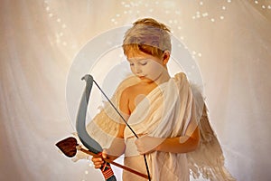 Little cupid toddle boy, holding bow and arrow, beautiful blond cherub