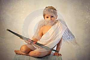 Little cupid toddle boy, holding bow and arrow, beautiful blond cherub