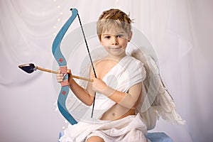 Little cupid toddle boy, holding bow and arrow, beautiful blond cherub