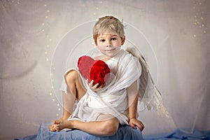 Little cupid toddle boy, holding bow and arrow, beautiful blond cherub