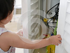 Little curious Asian baby girl`s hands open a cabinet of daddy`s mechanic tools