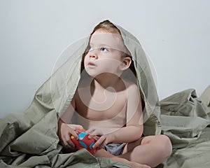 Little curly blonde boy playing in the bed