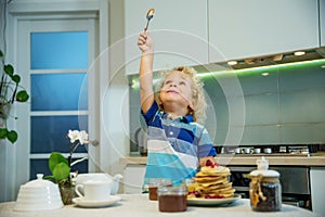 Little curly boy eating sweet pancakes