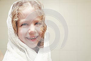 Little curly girl in towel in bathroom.