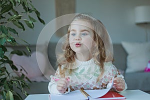 Little curly-haired cute blue-eyed girl 4 years old in a cozy house. Portrait of a happy child