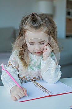 Little curly-haired cute blue-eyed girl 4 years old in a cozy house. Portrait of a happy child