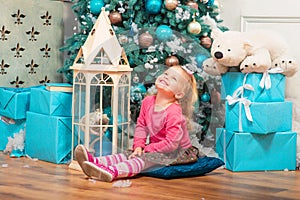 Little curly smiling girl standing nearly Christmas tree