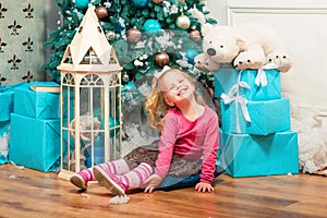 Little curly smiling girl standing nearly Christmas tree