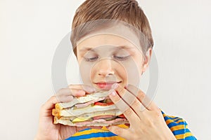 Little cut boy in a striped shirt with a tasty sandwich on white background