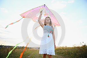 Little cute 7 years old girl running in the field with kite on summer day