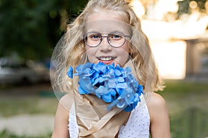 Little cute adorable blond caucasian little female child girl portrait hold beautiful fresh blue hydrangea bouquet