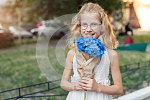 Little cute adorable blond caucasian little female child girl portrait hold beautiful fresh blue hydrangea bouquet