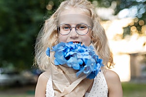 Little cute adorable blond caucasian little female child girl portrait hold beautiful fresh blue hydrangea bouquet