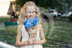 Little cute adorable blond caucasian little female child girl portrait hold beautiful fresh blue hydrangea bouquet