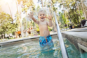 Little cute adorable blond playful beautiful caucasian active toodler boy enjoy playing at pool edge at summertime