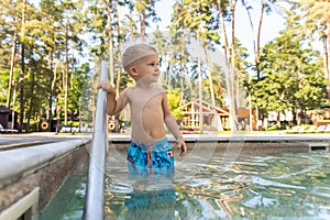 Little cute adorable blond playful beautiful caucasian active toodler boy enjoy playing at pool edge at summertime