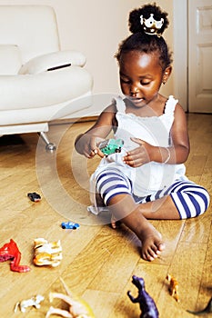 Little cute african american girl playing with animal toys at ho