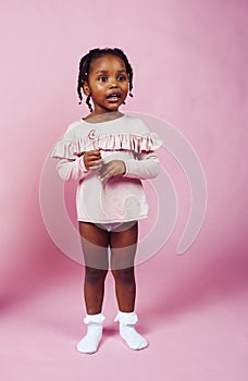 Little cute african girl posing cheerful inocent on pink background, lifestyle people concept