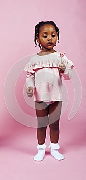 Little cute african girl posing cheerful inocent on pink background, lifestyle people concept