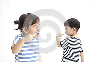 A little cute asian girl brushing her teeth isolated on white background.