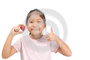 Little cute asian girl holding a strawberry and showing thumb up