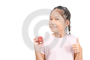 Little cute asian girl holding a strawberry and showing thumb up