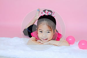 Little cute asian girl playing pink balls on pink background
