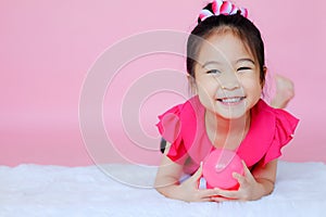 Little cute asian girl playing pink balls on pink background