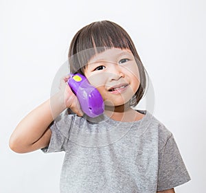 Little cute asian girl talking with the plastic phone.
