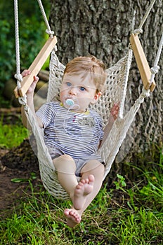 Little cute baby boy riding on hammock swing at park