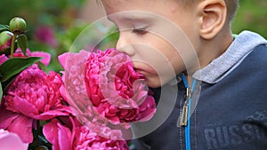 A little cute baby gently enjoys the smell of flowers. The child picks up a flower and inhales its fragrance. Blossoming photo