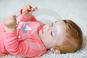 Little cute baby girl learning to crawl. Healthy child crawling in kids room with colorful toys. Back view of baby legs