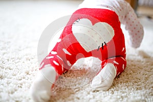 Little cute baby girl learning to crawl. Healthy child crawling in kids room with colorful toys. Back view of baby legs