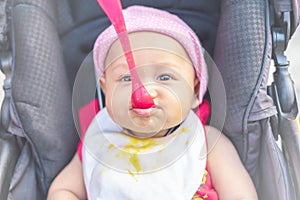 Little cute baby girl sits on a chair and eating with spoon. Mother feeding baby holding out her hand with a spoon of food made