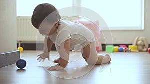 Little, cute baby girl, toddler crawling to toy on floor at home in the morning. Playful, healthy, beautiful baby