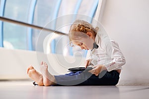 Little cute barefoot girl sits on floor and plays