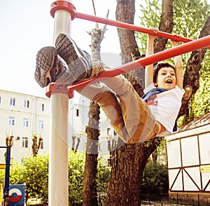 Little cute blond boy hanging on playground outside, alone training with fun, lifestyle children concept