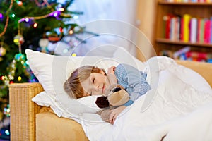 Little cute blond child sleeping under Christmas tree