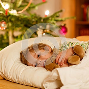 Little cute blond child sleeping under Christmas tree