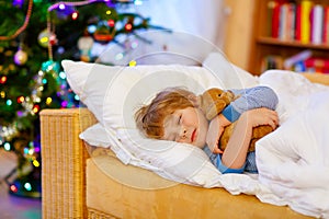 Little cute blond child sleeping under Christmas tree